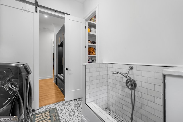 bathroom featuring tile patterned flooring, washer / dryer, and a shower