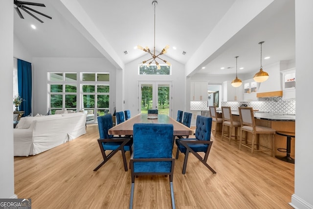 dining space featuring light hardwood / wood-style floors, ceiling fan with notable chandelier, french doors, and high vaulted ceiling