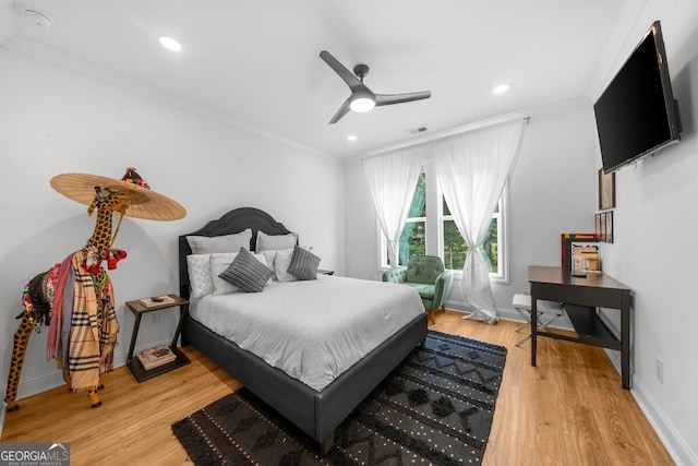 bedroom featuring ceiling fan, crown molding, and light hardwood / wood-style flooring