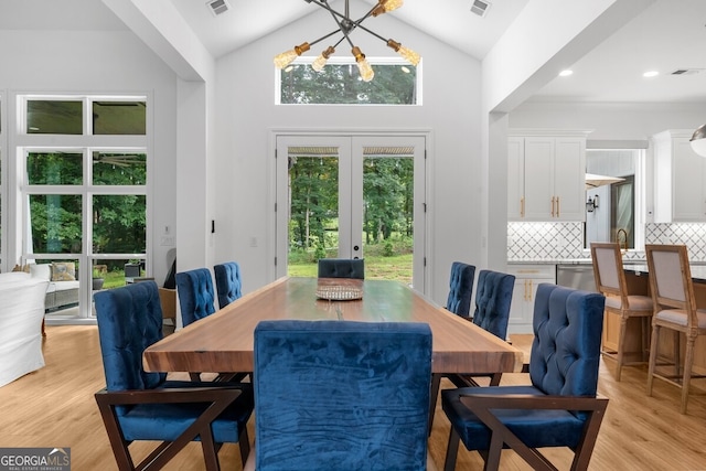 dining space featuring french doors, a chandelier, light wood-type flooring, sink, and high vaulted ceiling