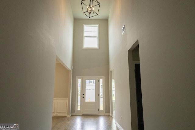 foyer with a chandelier, a towering ceiling, and light hardwood / wood-style floors