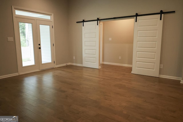 interior space featuring a barn door, dark hardwood / wood-style flooring, and french doors