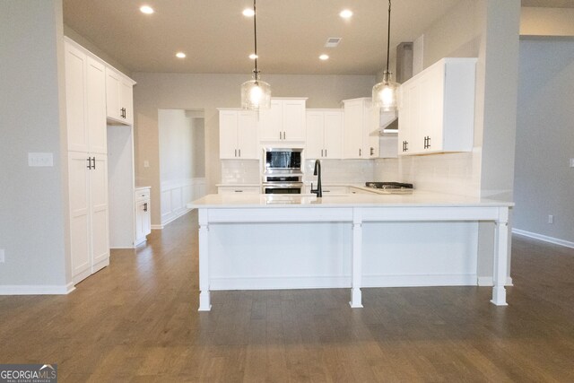 kitchen with kitchen peninsula, decorative light fixtures, stainless steel appliances, and white cabinets