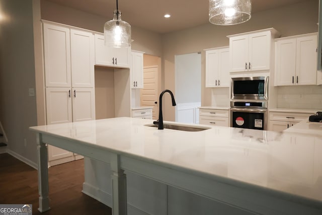 kitchen with backsplash, stainless steel appliances, sink, decorative light fixtures, and white cabinetry