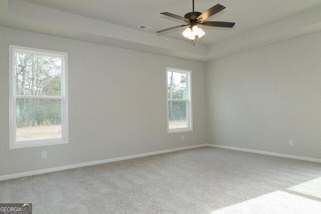 carpeted spare room with a tray ceiling and ceiling fan