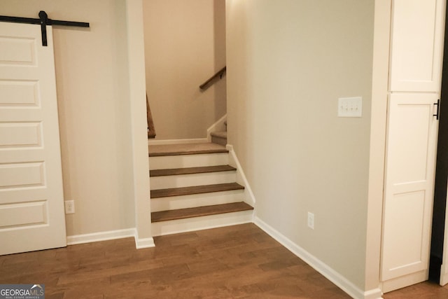 stairs with wood-type flooring and a barn door