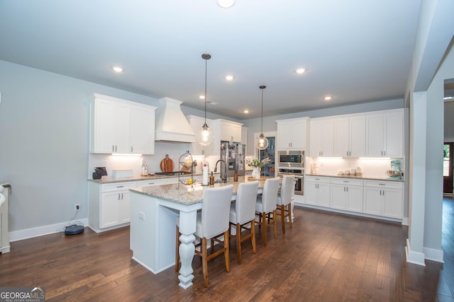 kitchen featuring dark wood-style floors, a kitchen breakfast bar, stainless steel appliances, and premium range hood