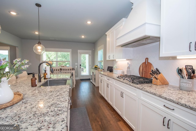 kitchen featuring white cabinets, dark hardwood / wood-style floors, a wealth of natural light, decorative light fixtures, and custom range hood