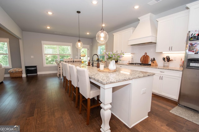 kitchen featuring white cabinetry, custom range hood, an island with sink, and dark wood-type flooring