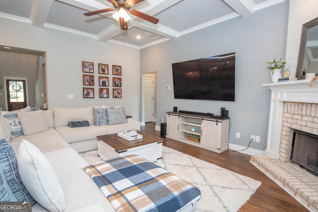 living room with ceiling fan, beam ceiling, dark wood-type flooring, and a brick fireplace