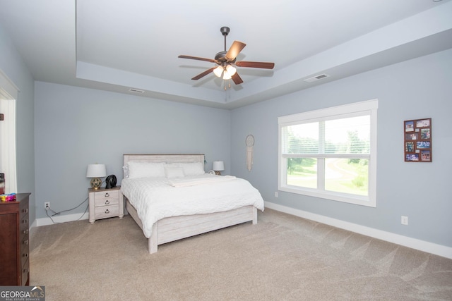 bedroom with carpet flooring, ceiling fan, and a raised ceiling