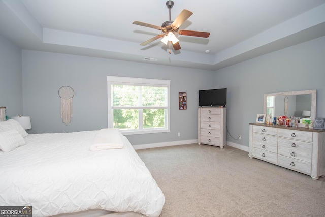 bedroom featuring a raised ceiling, ceiling fan, and light colored carpet