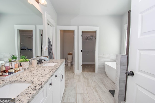 full bath with a sink, a soaking tub, double vanity, and toilet