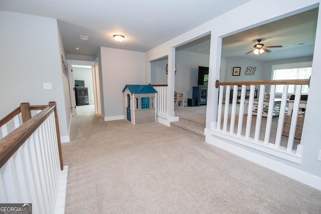 hallway with an upstairs landing, light colored carpet, and baseboards