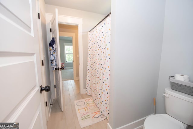 bathroom with curtained shower, toilet, and wood finished floors