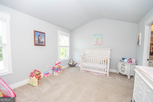 bedroom featuring a crib, light carpet, and vaulted ceiling