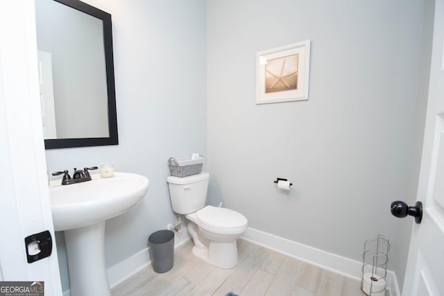 bathroom with wood-type flooring, toilet, and sink