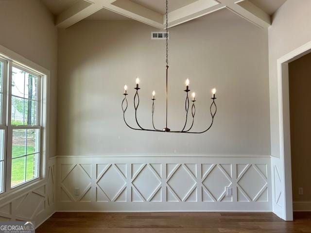interior details with a wainscoted wall, visible vents, wood finished floors, and a chandelier