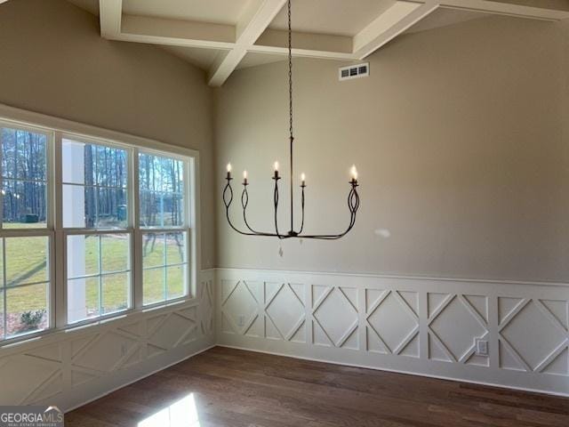 unfurnished dining area with a chandelier, visible vents, coffered ceiling, dark wood-style floors, and beam ceiling