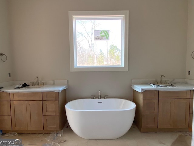 full bathroom featuring a soaking tub, marble finish floor, and two vanities