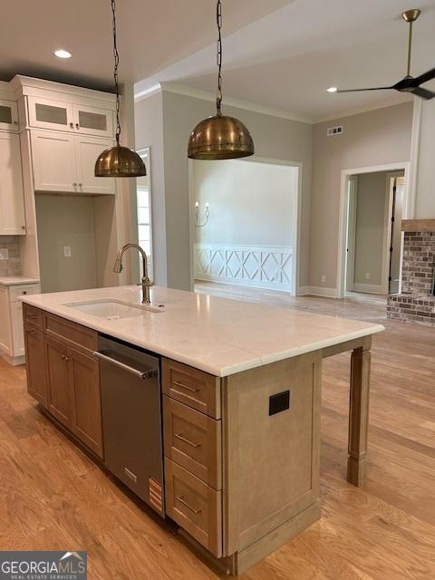 kitchen with a sink, dishwasher, ornamental molding, and white cabinetry