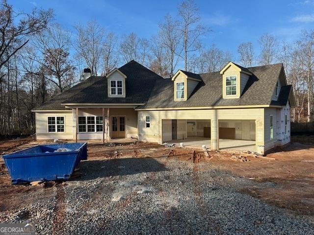 cape cod house featuring gravel driveway and an attached garage