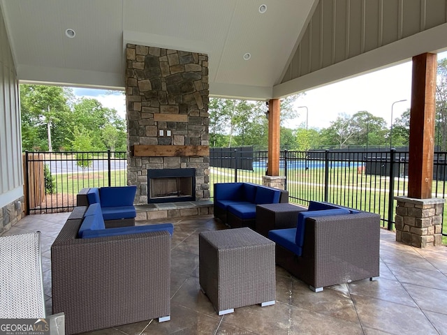 view of patio with an outdoor living space with a fireplace and fence