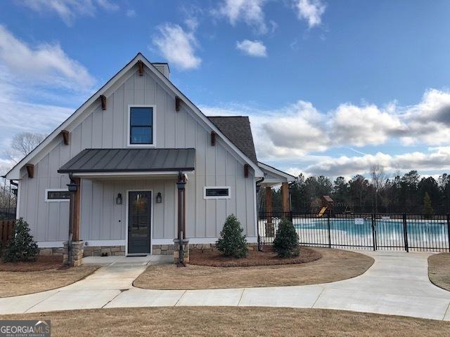 modern farmhouse featuring a standing seam roof, metal roof, a fenced in pool, board and batten siding, and fence