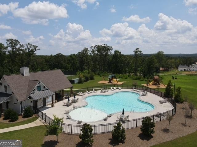 pool featuring a yard, playground community, a patio area, and fence