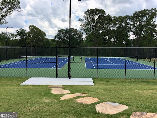 view of tennis court featuring a lawn, community basketball court, and fence