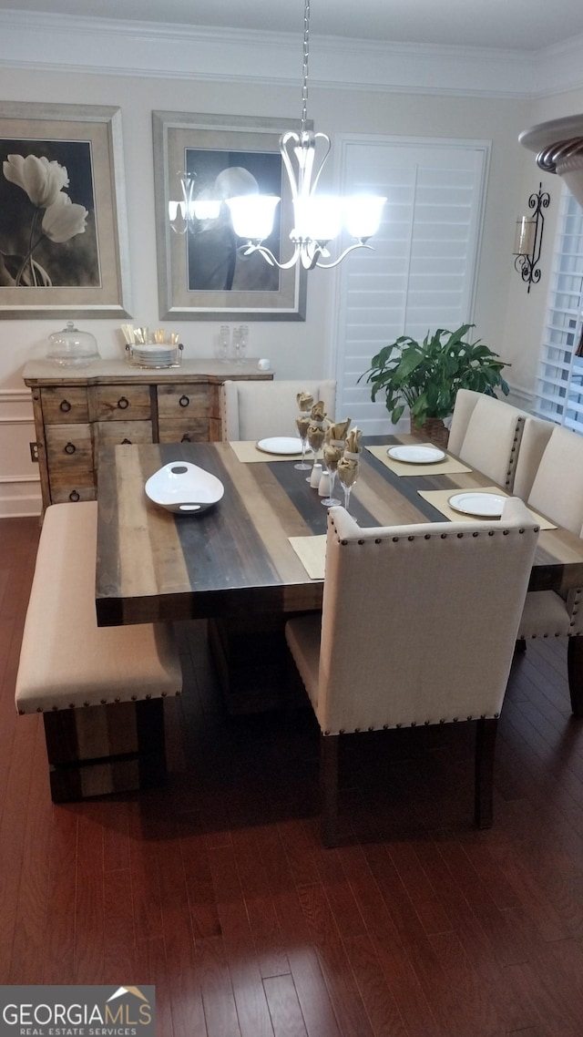 dining space with crown molding, dark hardwood / wood-style flooring, and an inviting chandelier