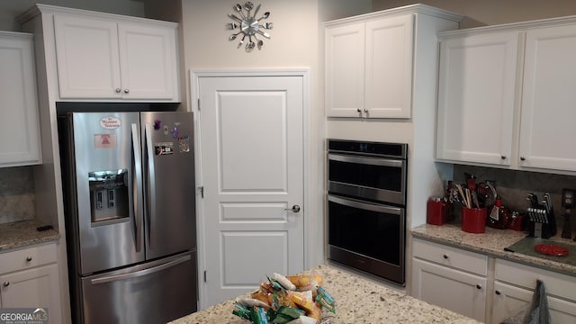 kitchen with light stone counters, tasteful backsplash, white cabinets, and appliances with stainless steel finishes