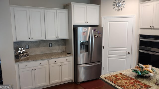 kitchen featuring white cabinetry, appliances with stainless steel finishes, backsplash, and light stone counters