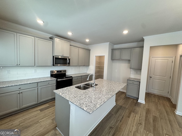 kitchen featuring tasteful backsplash, sink, appliances with stainless steel finishes, and an island with sink