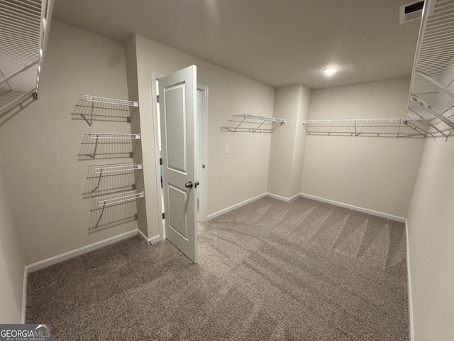 walk in closet with dark carpet