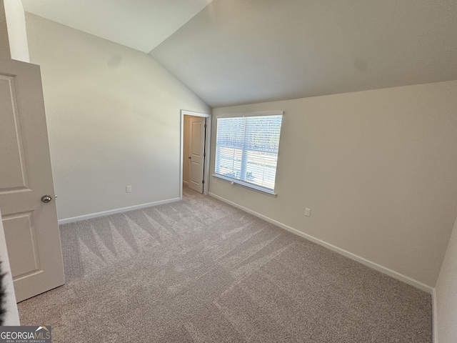 carpeted empty room featuring lofted ceiling