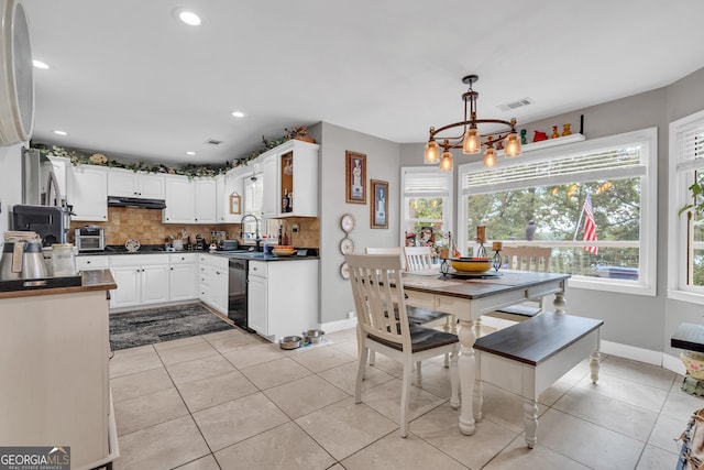 kitchen featuring backsplash, white cabinets, pendant lighting, dishwasher, and a chandelier