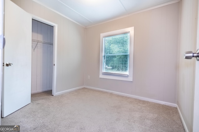 unfurnished bedroom with light carpet, a closet, and ornamental molding