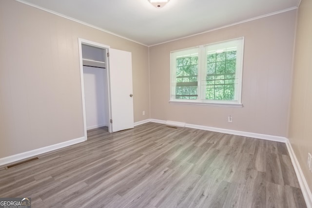 unfurnished bedroom with light wood-type flooring, a closet, and ornamental molding