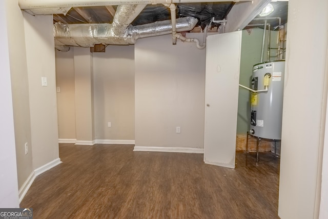 basement with dark hardwood / wood-style flooring and water heater