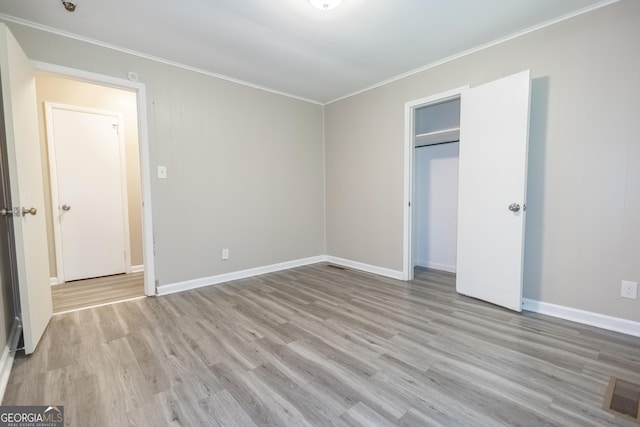 unfurnished bedroom with light hardwood / wood-style flooring, a closet, and crown molding