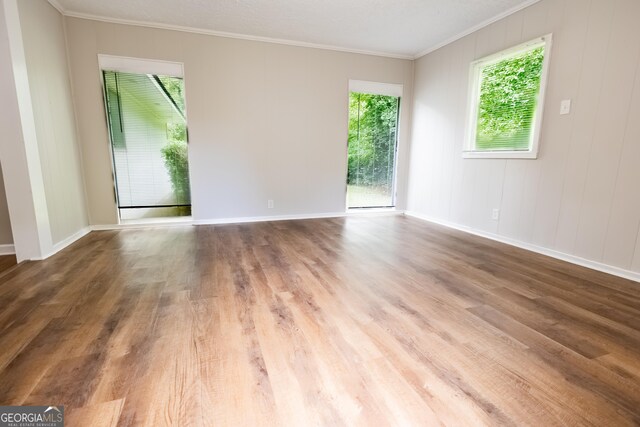 unfurnished room featuring wood-type flooring and crown molding