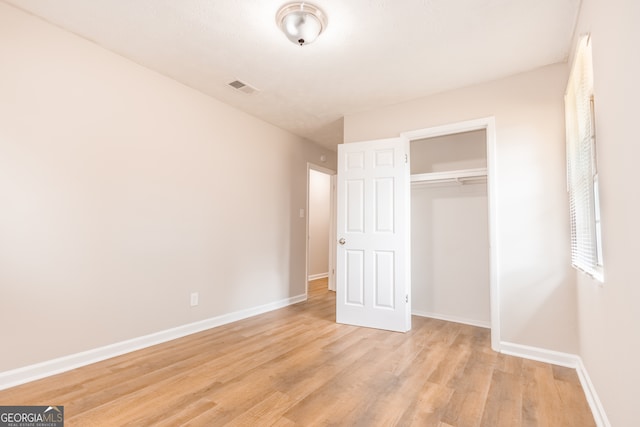 unfurnished bedroom featuring light wood-type flooring and a closet