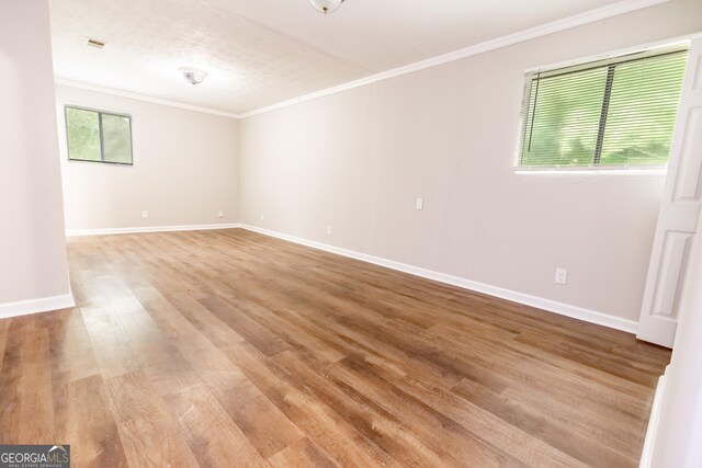 spare room featuring crown molding and light hardwood / wood-style flooring