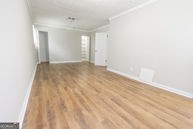 empty room with crown molding and light hardwood / wood-style floors