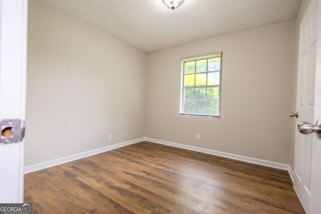 unfurnished room with dark wood-type flooring