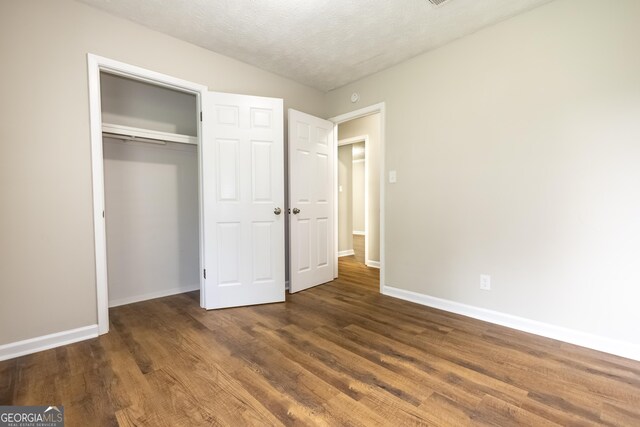 unfurnished bedroom featuring a textured ceiling, a closet, and wood-type flooring