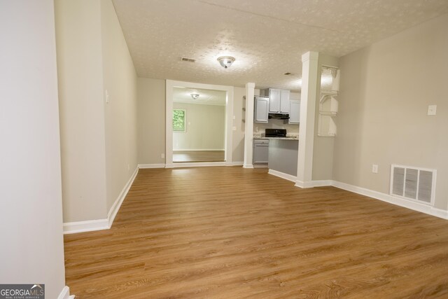 unfurnished living room with light hardwood / wood-style flooring and a textured ceiling