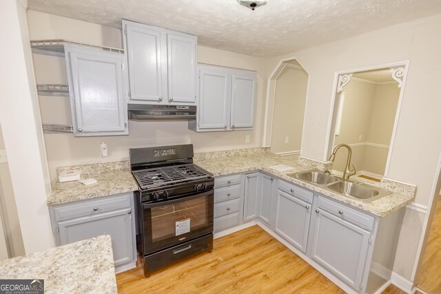 kitchen featuring light hardwood / wood-style floors, black gas range, sink, and a textured ceiling