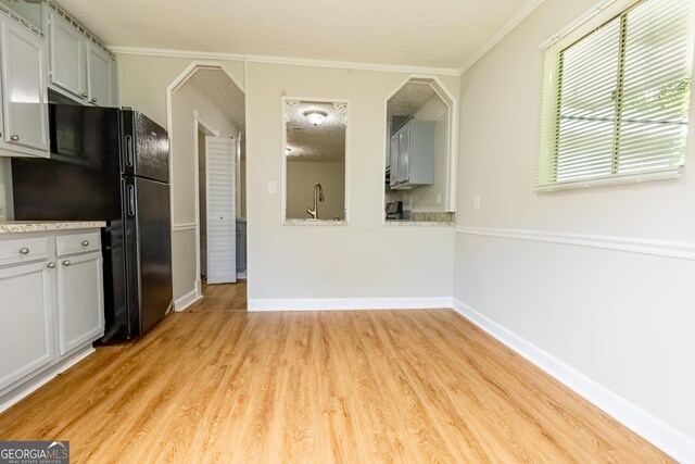 kitchen with sink, gray cabinets, light hardwood / wood-style floors, black fridge, and ornamental molding